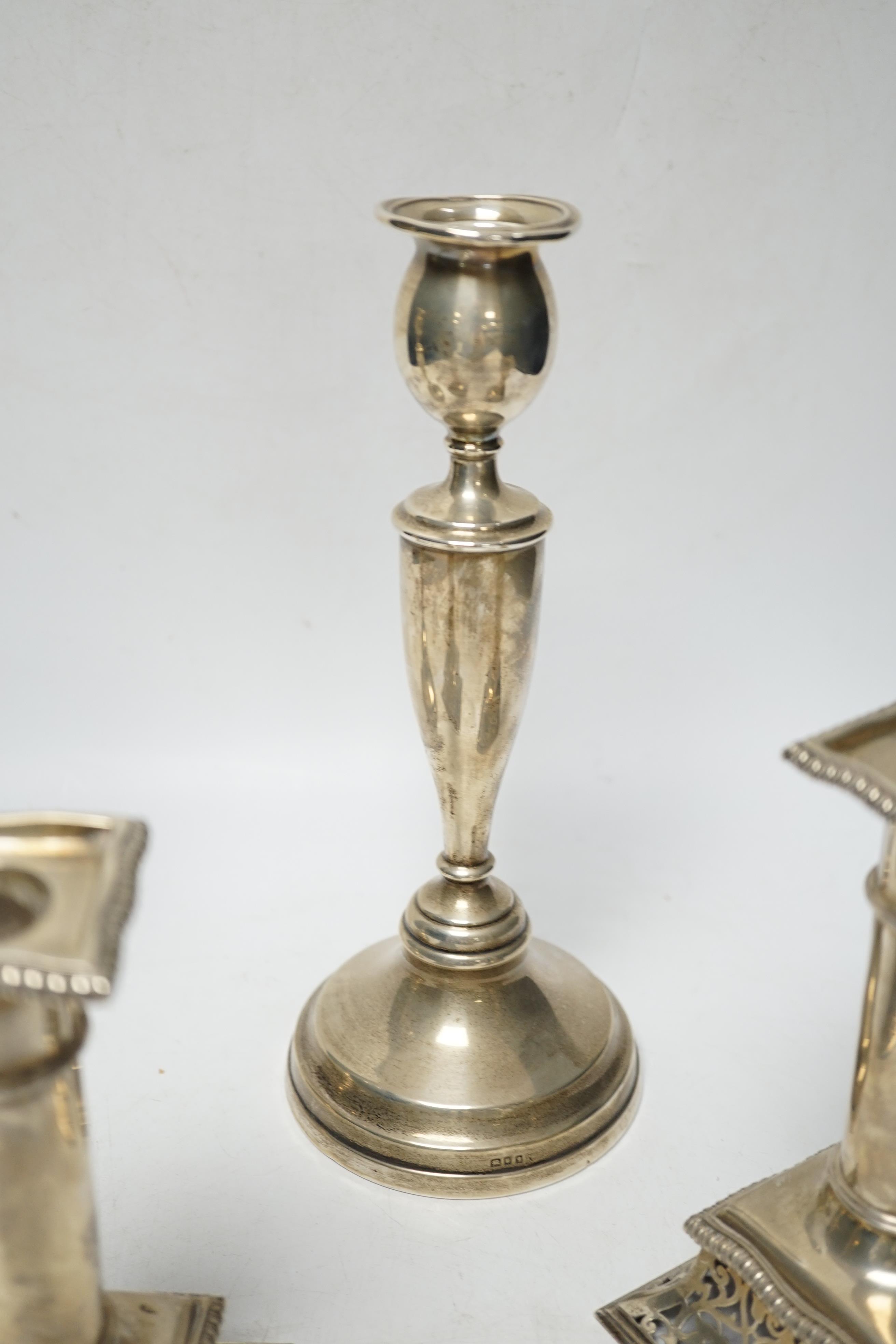 A pair of Victorian silver candlesticks, on pierced swept bases, William Leuchars, London, 1886, 15.2cm, weighted and a later taller pair of silver candlesticks.
